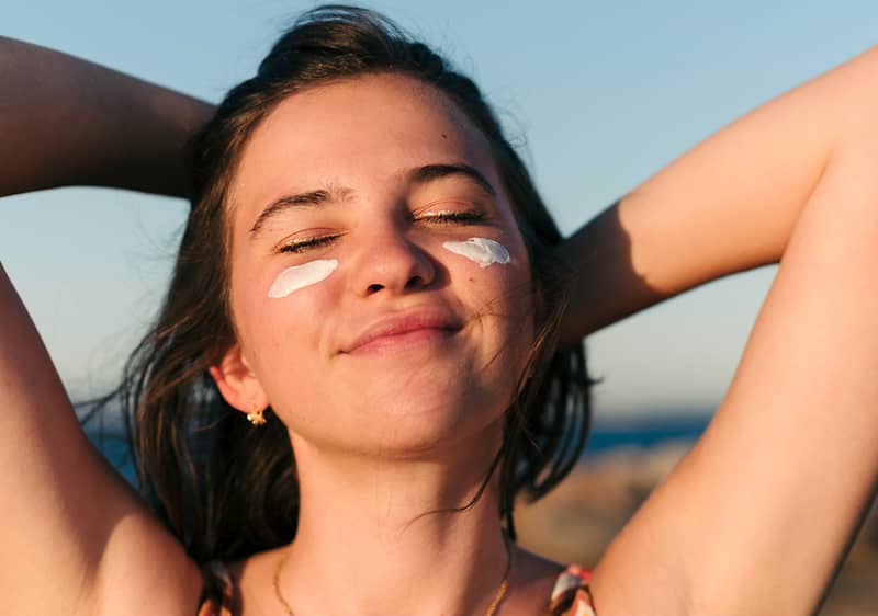 Frau mit Sonnencreme im Gesicht
