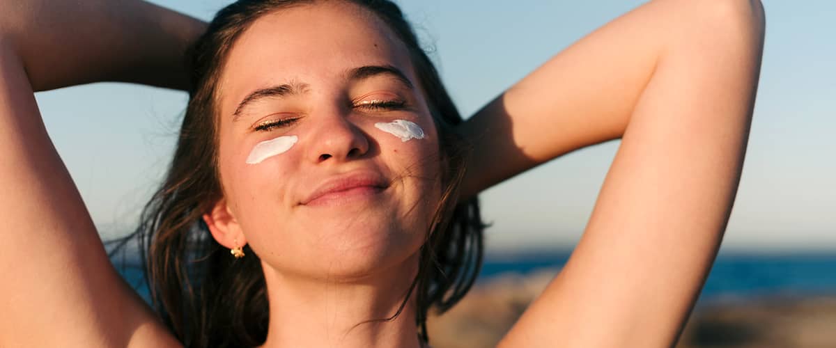 Frau mit Sonnencreme im Gesicht