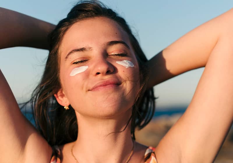 Frau mit Sonnencreme im Gesicht