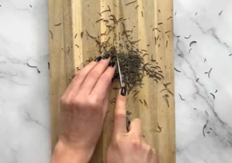 Rosmarin wird auf Schneidebrett geschnitten