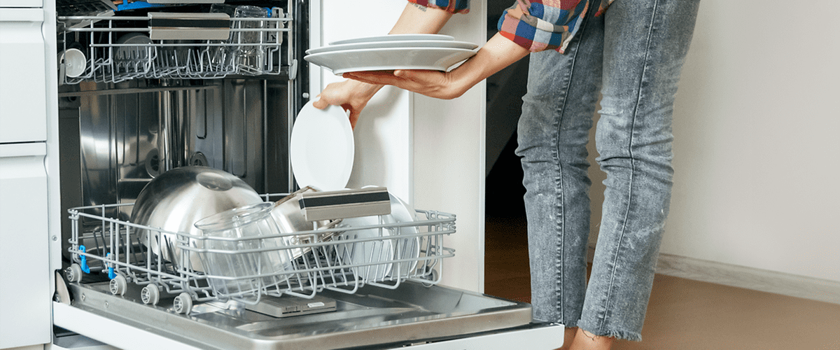 Frau, die gerade Geschirrspülmaschine einräumt