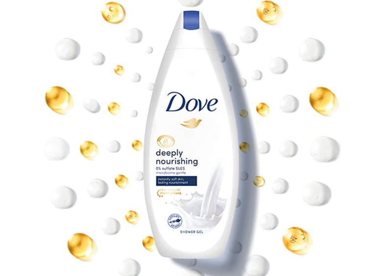 Slika koja prikazuje bocu Dove deeply nourishing tuš gela okruženu zlatnim i belim kapljicama