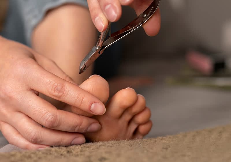 Frau schneidet Zehennägel