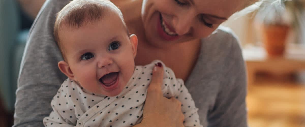 Lächelnde Mutter hält lachendes Baby im Arm