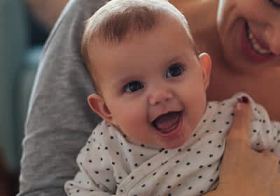 Lächelnde Mutter hält lachendes Baby im Arm