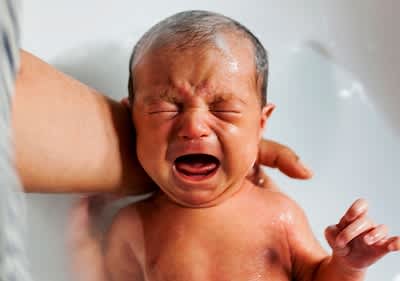 Baby wird gebadet und weint
