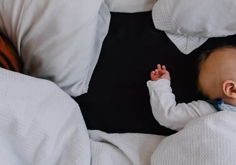 Baby liegt gut zugedeckt im Bett