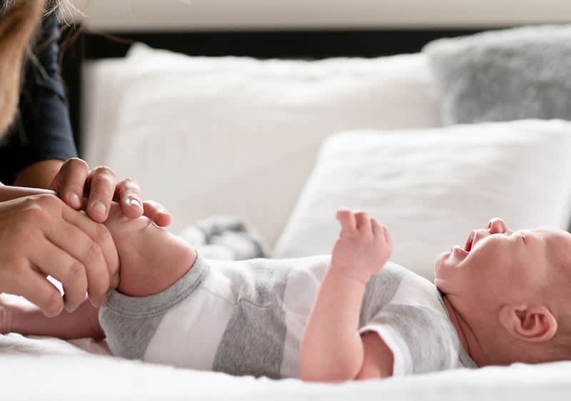 Weinendes Baby liegt auf einem Bett