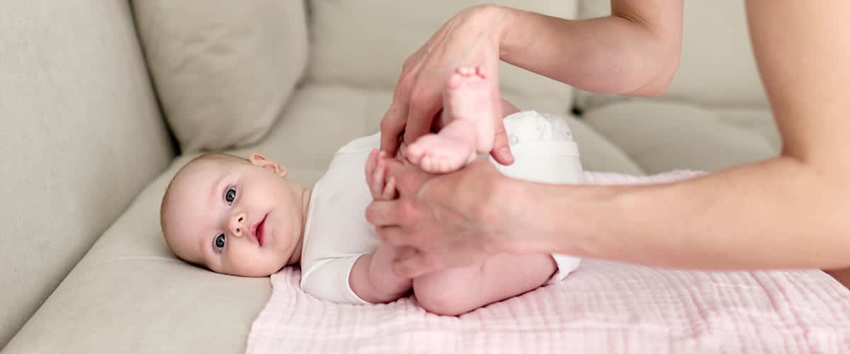 Baby liegt auf Sofa und wird massiert
