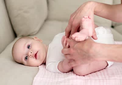 Baby liegt auf Sofa und wird massiert