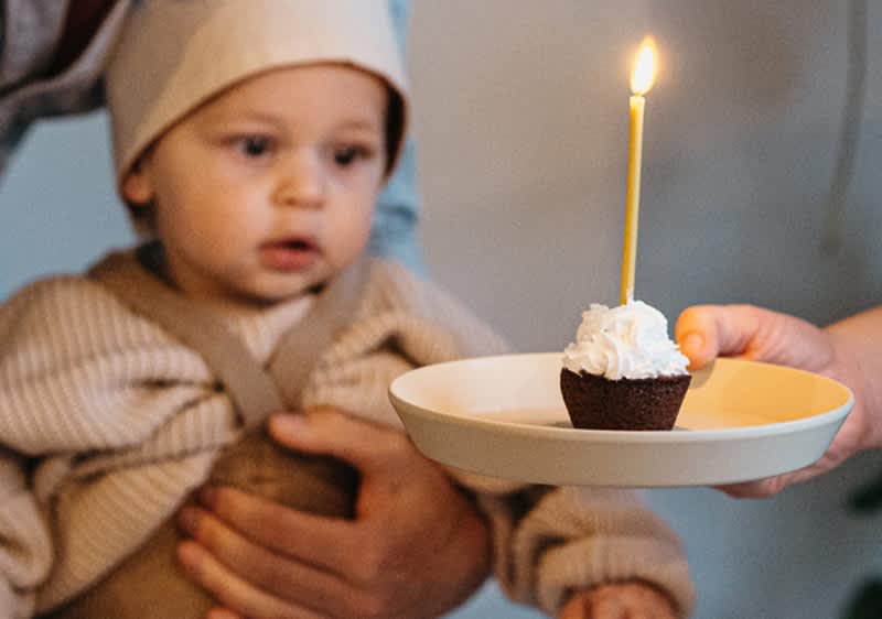 Baby bestaunt erste Geburtstagskerze auf Muffin