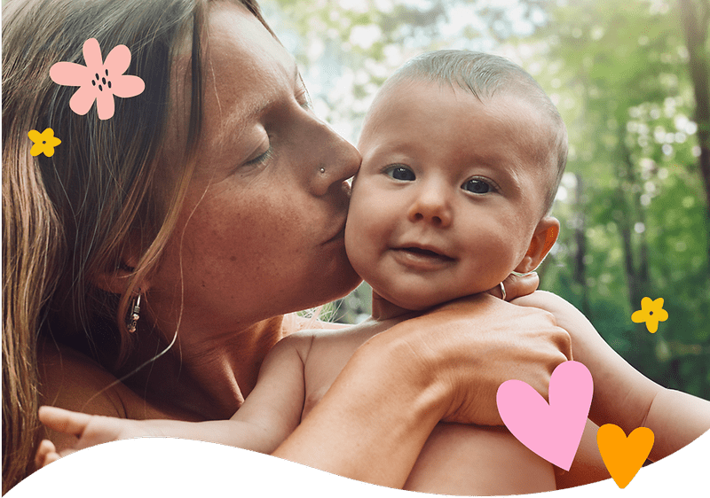 Mutter mit Baby im Freien umgeben von Pflanzen und Blumen