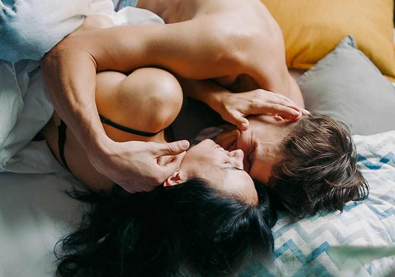 Mann und Frau liegen im Bett und kuscheln