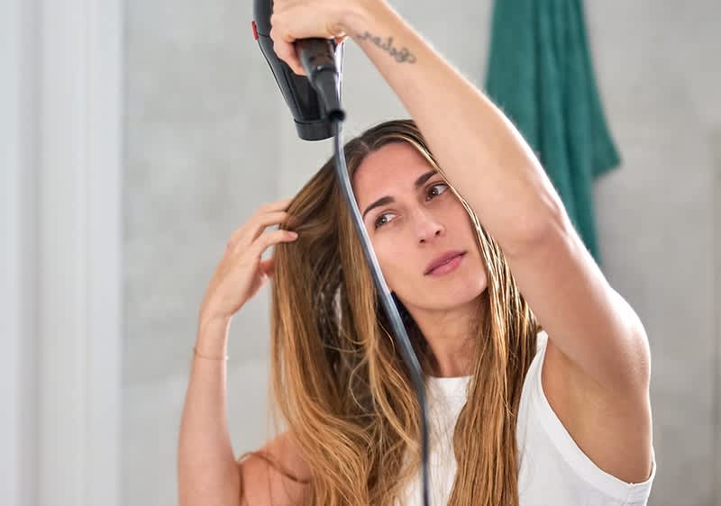 Frau mit langen braunen Haaren beim Foehnen