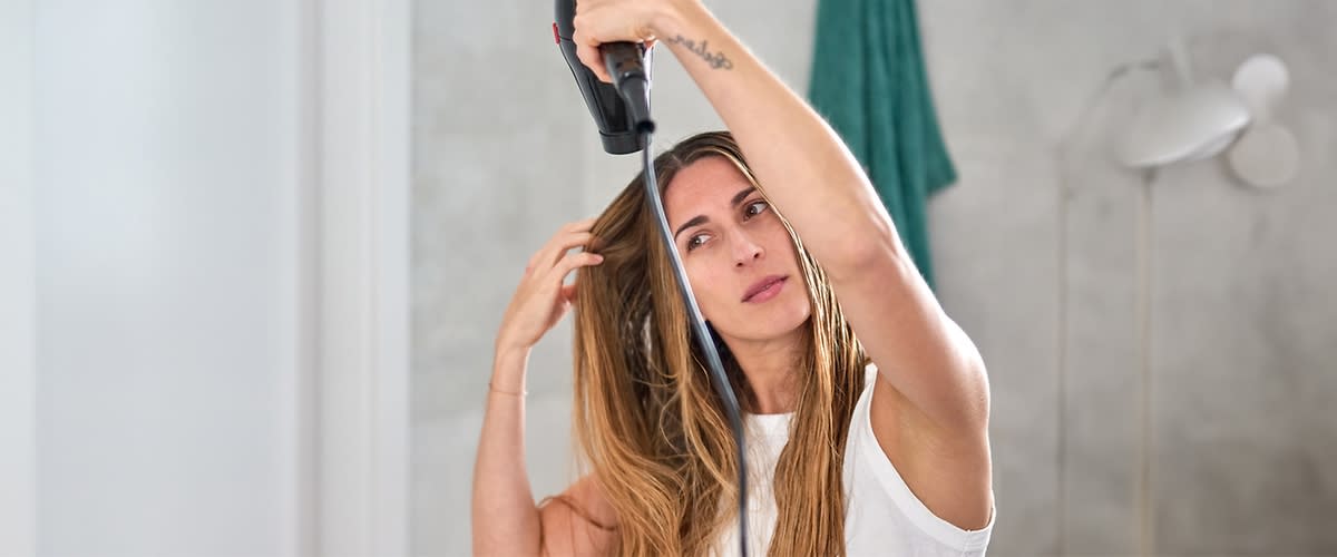Frau mit langen braunen Haaren beim Foehnen