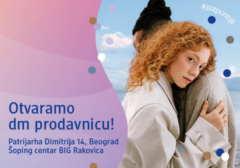 Slika koja prikazuje par zagrljen ispred plakata za otvaranje dm prodavnice