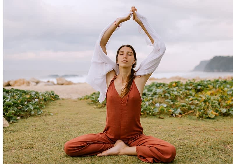 Slika koja prikazuje ženu kako meditira na obali mora ključna reč meditacija