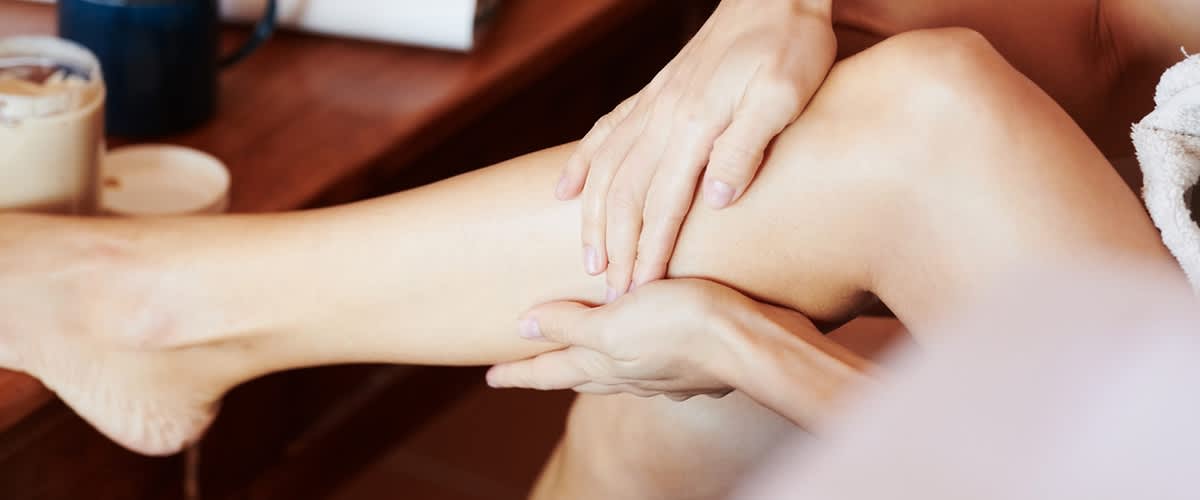Slika koja prikazuje masažu noge sa rukama terapeuta