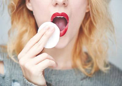 Frau schminkt sich roten Lippenstift ab.