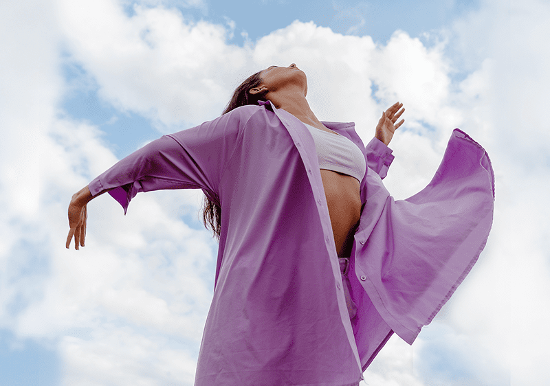 Frau mit lila Bluse schaut in den Himmel