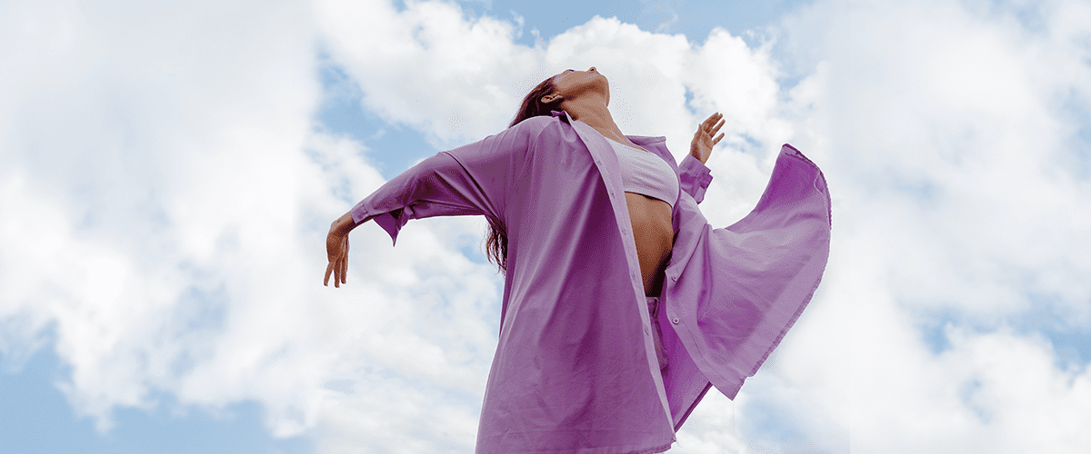 Frau mit lila Bluse schaut in den Himmel